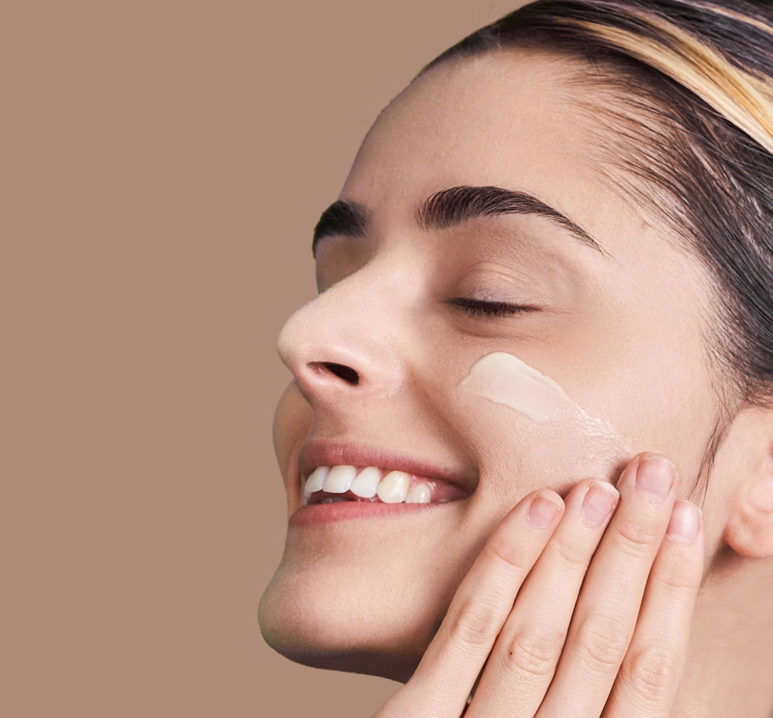 happy woman applying skincare cream to her face